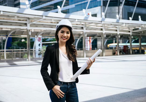 A female civil engineering intern is posing at the construction site