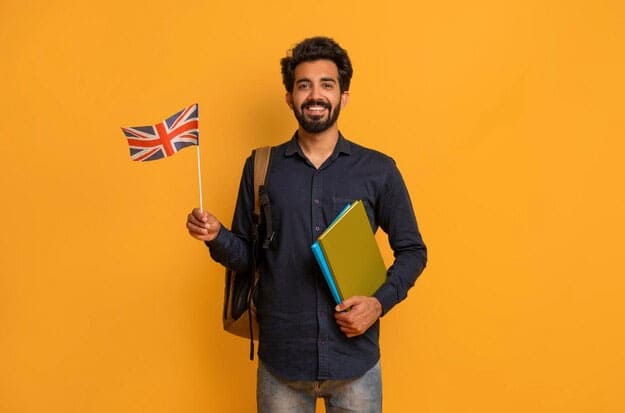 An excited male student stands with a Union Jack in his right hand and a file in the other
