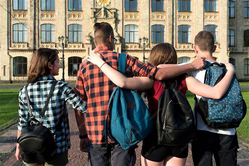group of friends holding one another moving towards a UK college